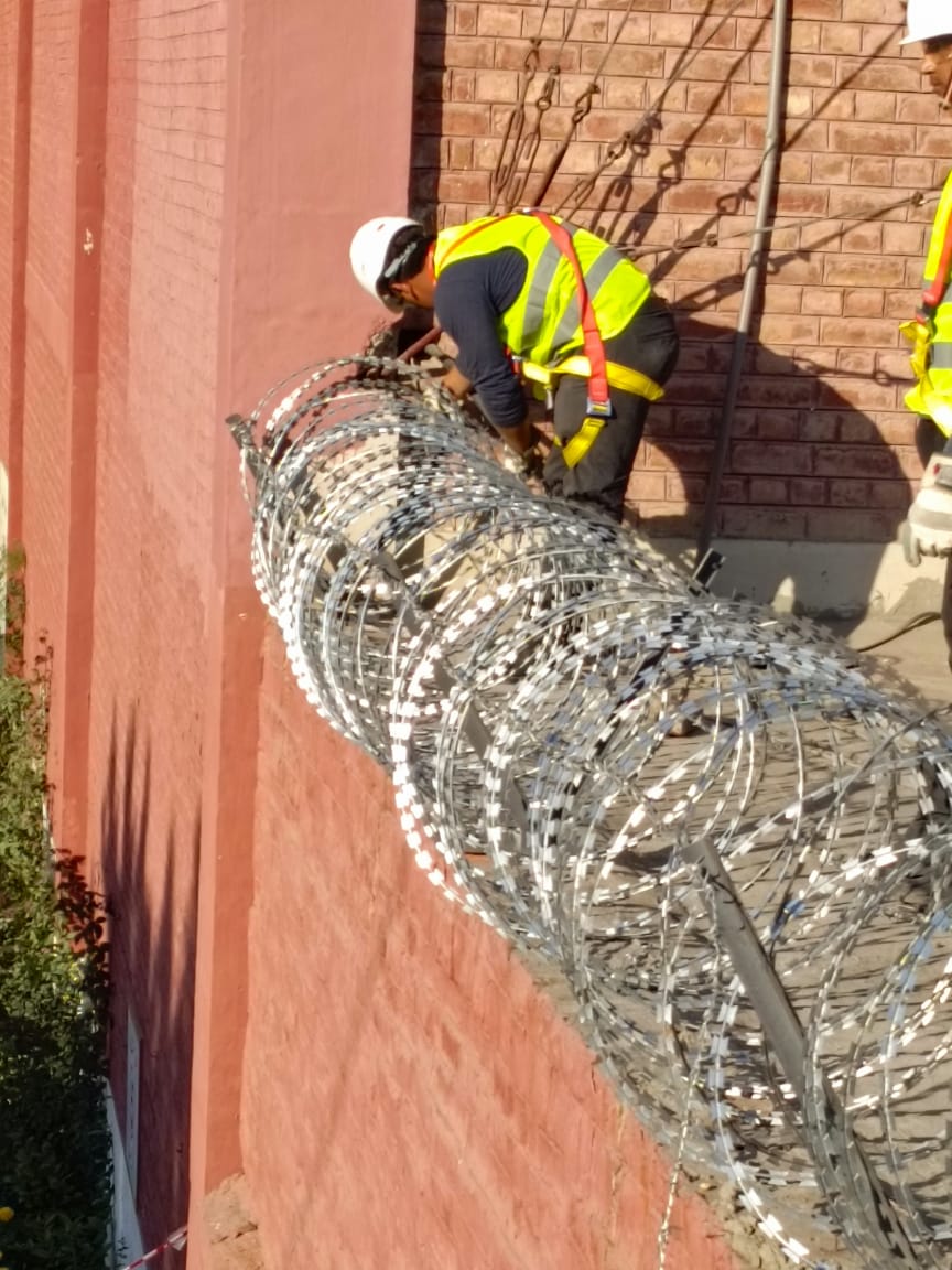 Workers installing concertina razor wire with PPE