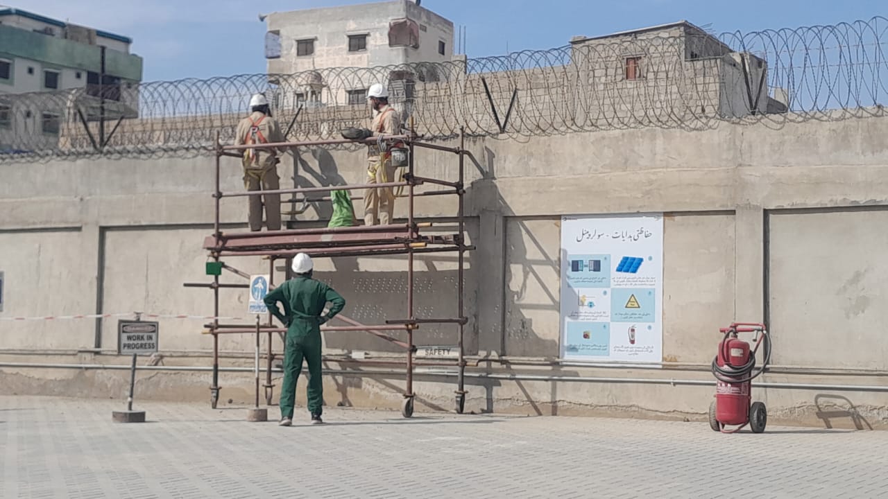 Workers on scaffold installing razor wire at oil and gas facility